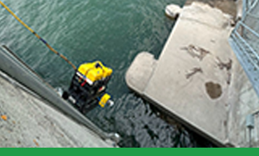 A remotely operated vehicle (ROV) is lowered into the river from the dam