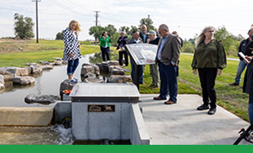 City Council Member stands on rock near hydro generation exhibit