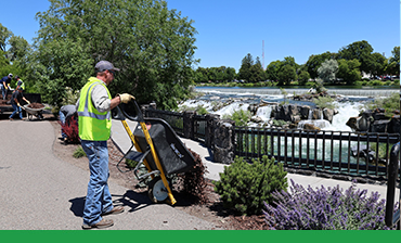Laying mulch in a garden bed with iconic Idaho Falls waterfall in the background